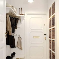 an entryway with white walls and wooden flooring, baskets on the wall, and coat rack