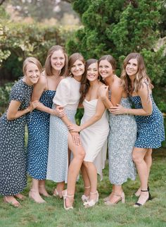 a group of women standing next to each other on top of a lush green field