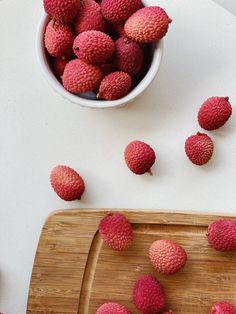 fresh raspberries sit on a cutting board next to a bowl of them