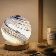 a white and black marble ball sitting on top of a wooden stand next to a candle