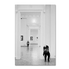 two people standing in an art gallery looking at paintings