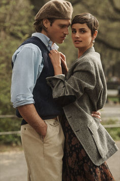 a man and woman standing next to each other in front of a tree filled forest