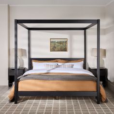 a four poster bed in a bedroom with carpeted flooring