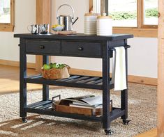 a black table with two drawers and a basket on it's shelf next to a window