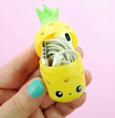 a hand holding a small yellow container with wires in it and a pineapple on top