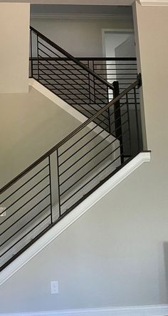 a stair case in the middle of a living room with an open door on one side