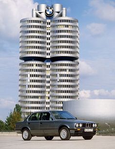 a car is parked in front of two tall buildings that look like they are stacked high