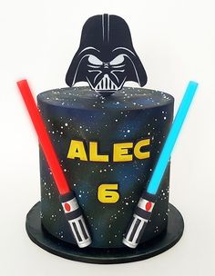 a star wars themed birthday cake with two lightsabes on top and a darth vader mask