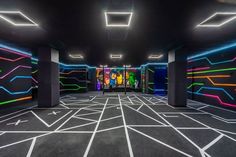 an empty room with neon lights on the walls and black carpeted flooring in front of it