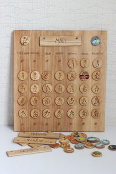 a wooden calendar sitting on top of a table next to some buttons and magnets