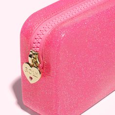 a pink glitter suitcase with a heart shaped lock on the handle and two small hearts attached to it