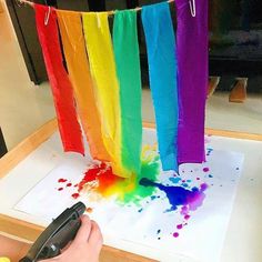 someone is using scissors to paint the rainbows on paper with colored watercolors