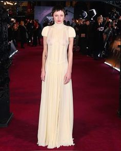 a woman in a white dress standing on a red carpet