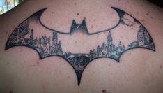 a batman tattoo on the back of a man's upper back shoulder and chest