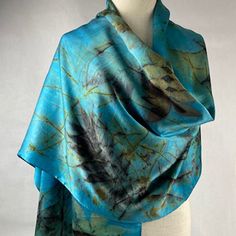 a mannequin wearing a blue and black scarf with feathers on the top of it