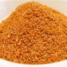 a white bowl filled with ground spices on top of a wooden table next to a knife and fork