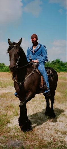 a man riding on the back of a brown horse in a field with grass and trees