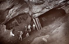 an old black and white photo of some people in front of a cave