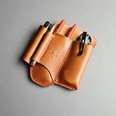 a leather pen case with two pens in it