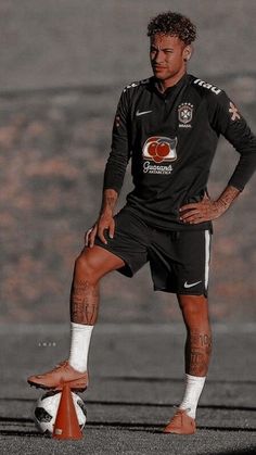 a soccer player is standing on the field with his foot in the air while holding onto an orange cone