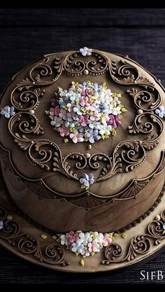 there is a chocolate cake decorated with flowers on the top and sides, sitting on a wooden platter