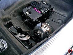 the inside of a car trunk with some wires and other items in it's compartment