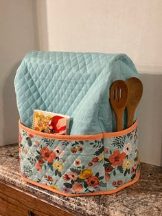 a blue quilted pot holder with utensils in it