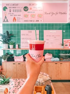 a person holding up a drink in front of a counter