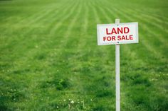 a land for sale sign sitting in the grass