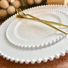 two white plates with gold forks on them