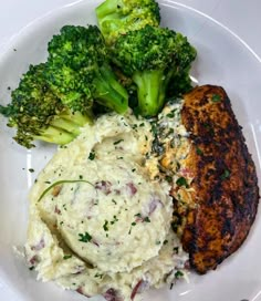 a white plate topped with meat, mashed potatoes and broccoli