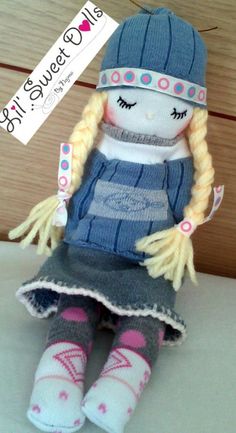 a small doll with long blonde hair and blue hat sitting on top of a table