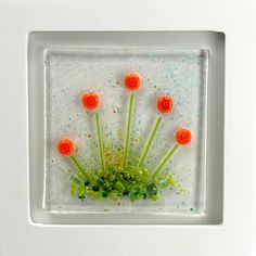 four orange and green flowers in a white frame with sprinkles on it