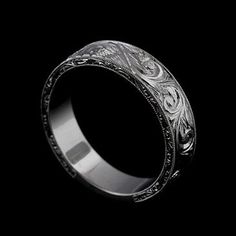 an intricately engraved wedding ring on a black background