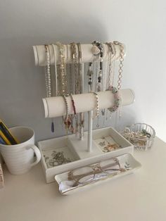 a white desk with various jewelry and glasses on it