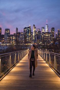 a woman standing on a bridge with the city skyline in the background and text brooklyn bridges park and dumbo