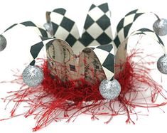 a close up of a paper crown on a white surface with red and silver decorations