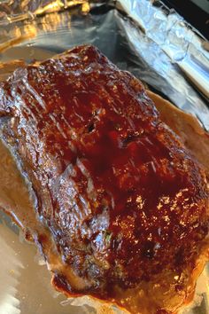 a piece of meat covered in bbq sauce sitting on top of foil lined baking sheet