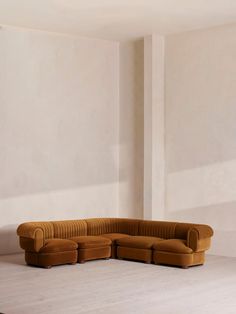 a large sectional couch sitting on top of a white floor next to a wall with two windows