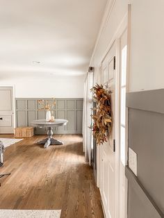 a living room with hard wood floors and white walls on the wall is decorated with wreaths