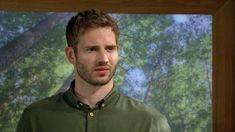 a man standing in front of a tree looking at the camera with a serious look on his face