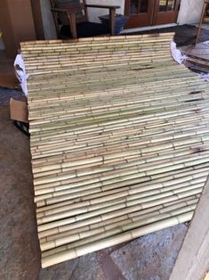 a pile of bamboo sitting on top of a wooden floor next to a building under construction