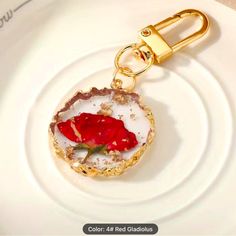 a white plate with a red flower on it and a gold keychain attached to it