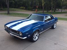 a blue and white muscle car parked in a driveway