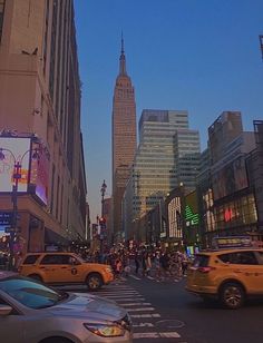 a busy city street filled with lots of traffic and tall buildings in the background at dusk