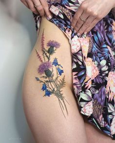 a woman's thigh with flowers and leaves on the bottom part of her thighs