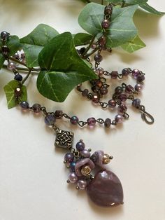 Stunning beaded pendant necklace features Czech glass florals with misty lilac pearls draping over a muted red jasper heart.  The linked chain part of this beauty patterns the same lilac pearls with more Czech glass beads in shades of grape and plum and small faceted purple lace agate rondelles.  Vintage finish brass wire and finding are used throughout including the graceful simple hook and loop clasp. Truly a treasure of color and bohemian style. * Measures 30" long with a 3" pendant drop * Re Misty Lilac, Czech Glass Necklace, Beauty Patterns, Muted Red, Necklace Amethyst, Beaded Pendant Necklace, Necklace Beaded, Purple Lace, Red Jasper