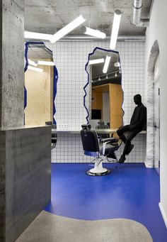 a man sitting on a chair in a room with blue flooring and white walls