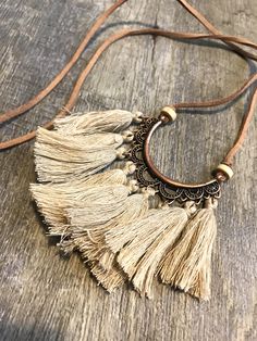 a necklace with tassels and beads hanging on a wooden surface, including a leather cord