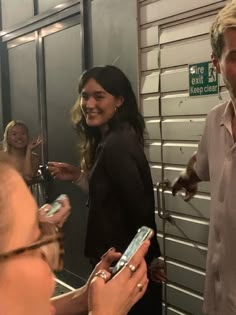 a man and woman standing in front of a mirror holding cell phones while smiling at each other